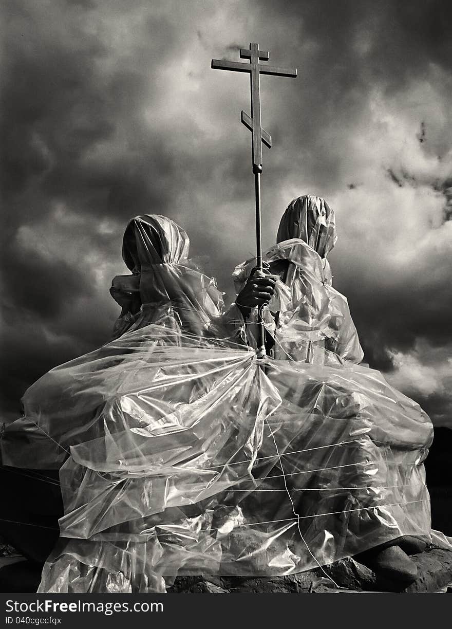 Cross and the religious sculpture closed by plastic wrap against the dramatic sky