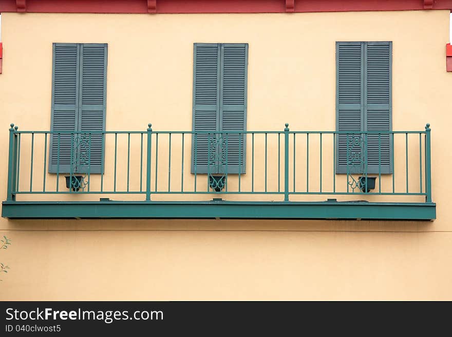 It is green whindows and fence on the yellow wall. It is green whindows and fence on the yellow wall.