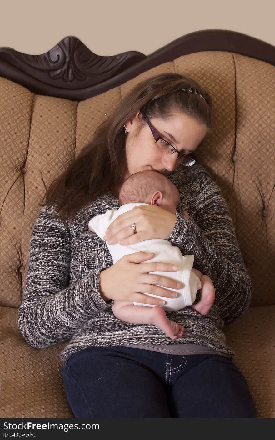 A mother holding her newborn son on the couch in a loving embrace. A mother holding her newborn son on the couch in a loving embrace.