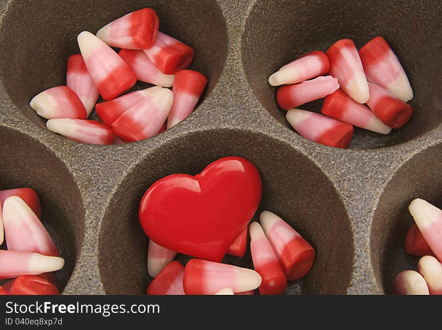 Valentine candy corn with red heart in a cast iron muffin pan. Valentine candy corn with red heart in a cast iron muffin pan.