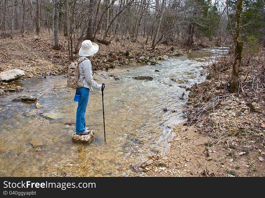 Hiker walking across a stream.