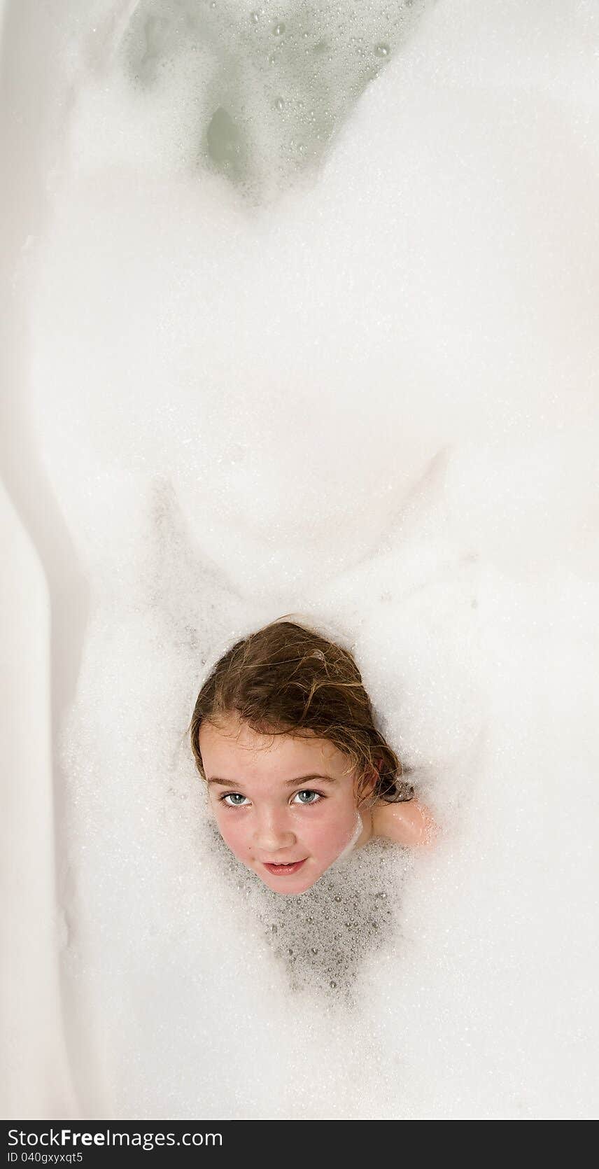 Little girl having fun in a bathtub full of soap foam. Little girl having fun in a bathtub full of soap foam.