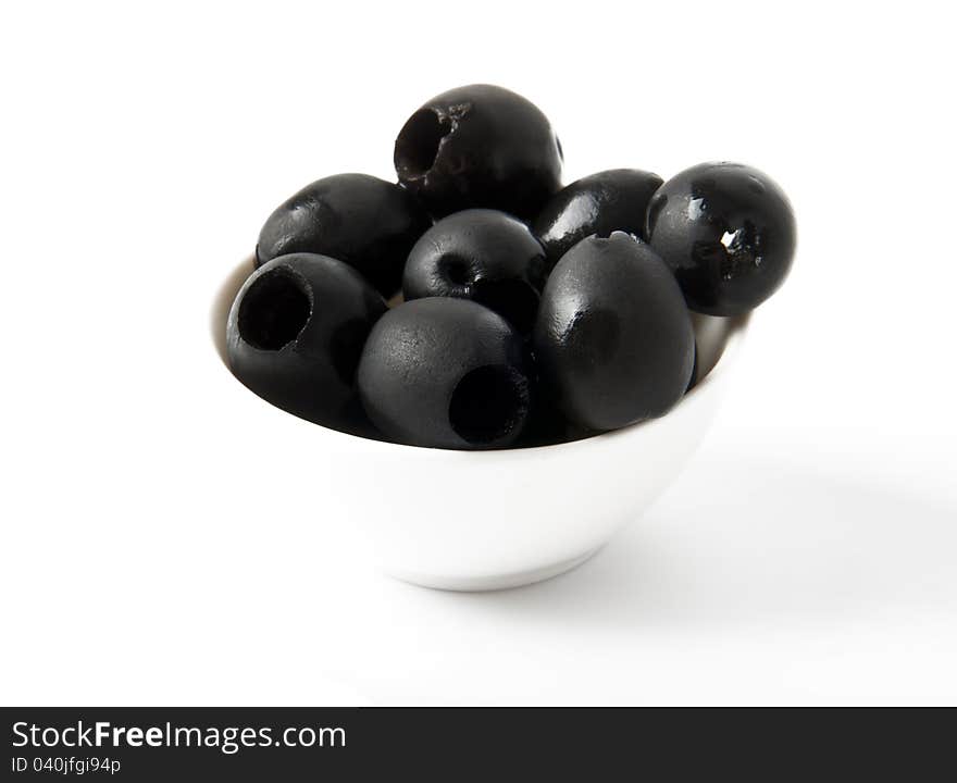 Black olives in a bowl on white