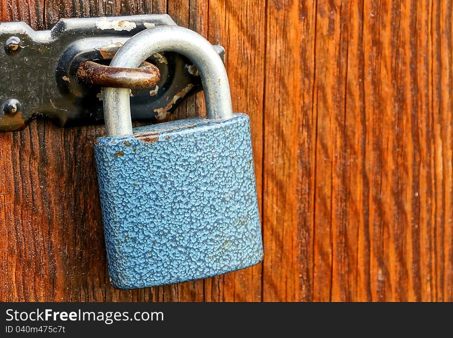 Blue padlock and black rusty haspa on wooden door