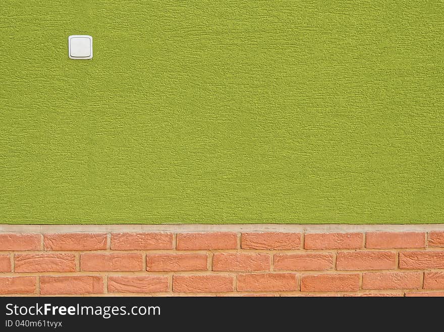 Green wall with bricks on bottom and white switch