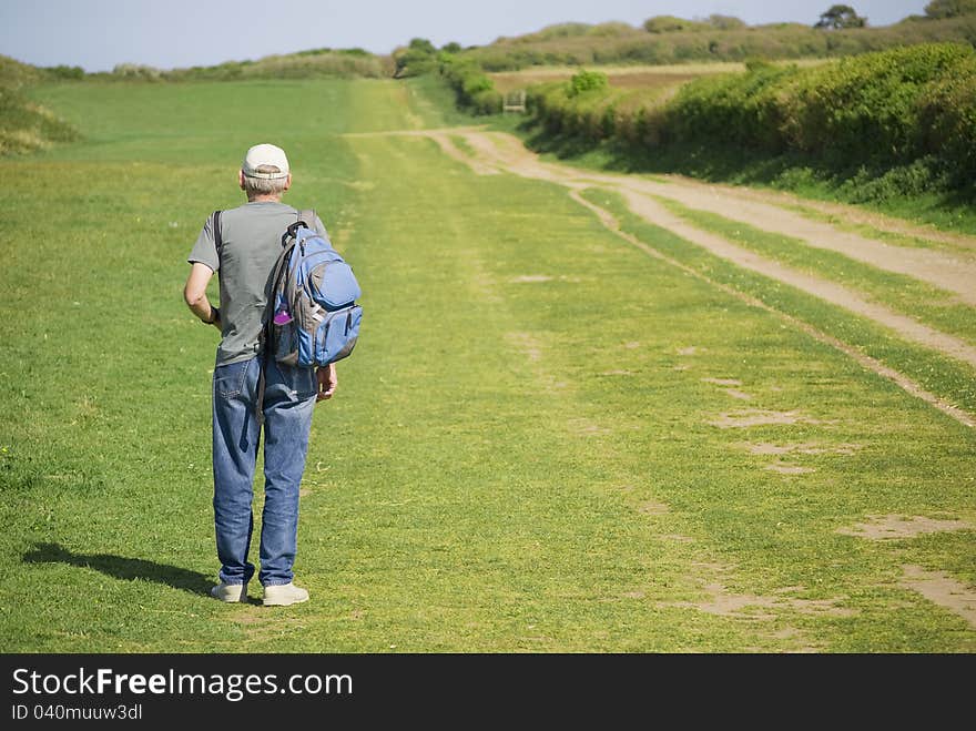 Senior man hiking over field in summer