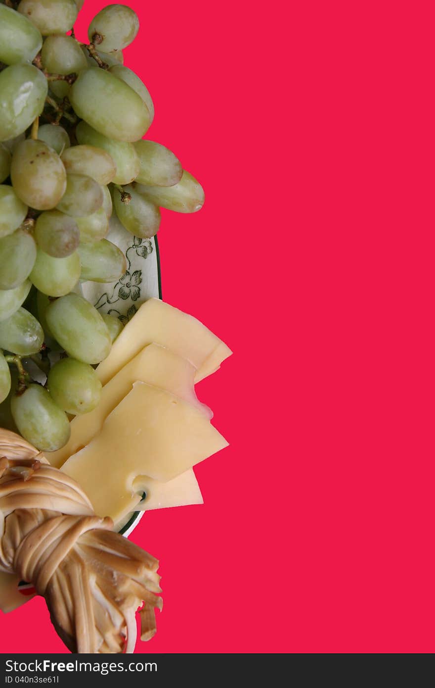 Cluster of white grapes, smoked cheese and Dutch cheese on a red background. Cluster of white grapes, smoked cheese and Dutch cheese on a red background