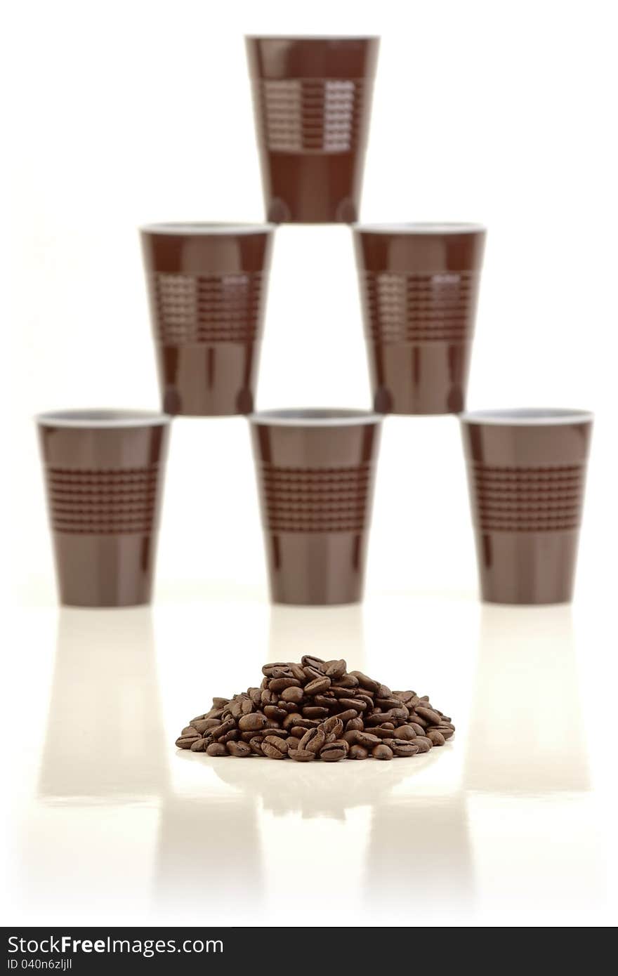 Pile of coffee beans and a stack of plastic cups arranged in the background on white. Pile of coffee beans and a stack of plastic cups arranged in the background on white.