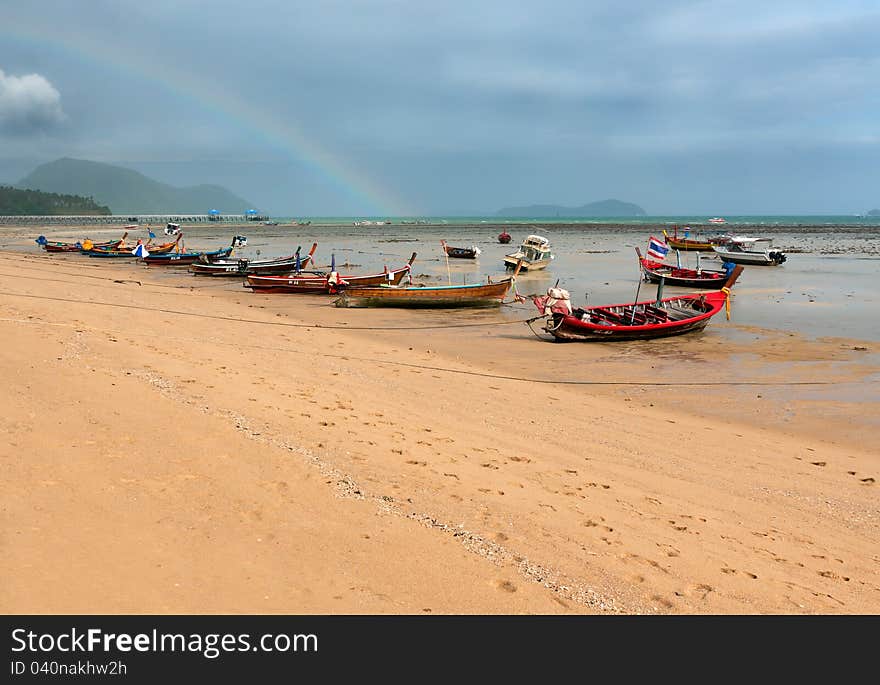 Ebb of the sea a boat on the rocks in the sky with a rainbow