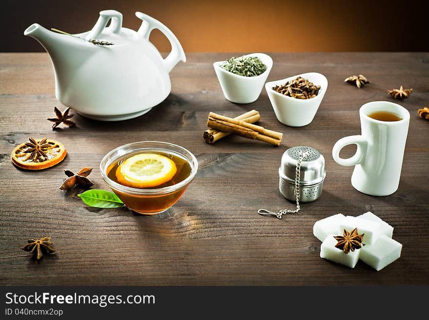 Hot tea in a teapot and bowls with spices on wooden. Hot tea in a teapot and bowls with spices on wooden