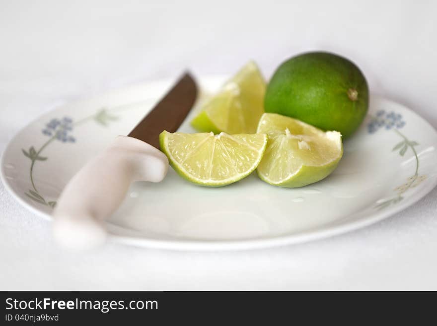 Pieces of cut lime and whole lime on a plate