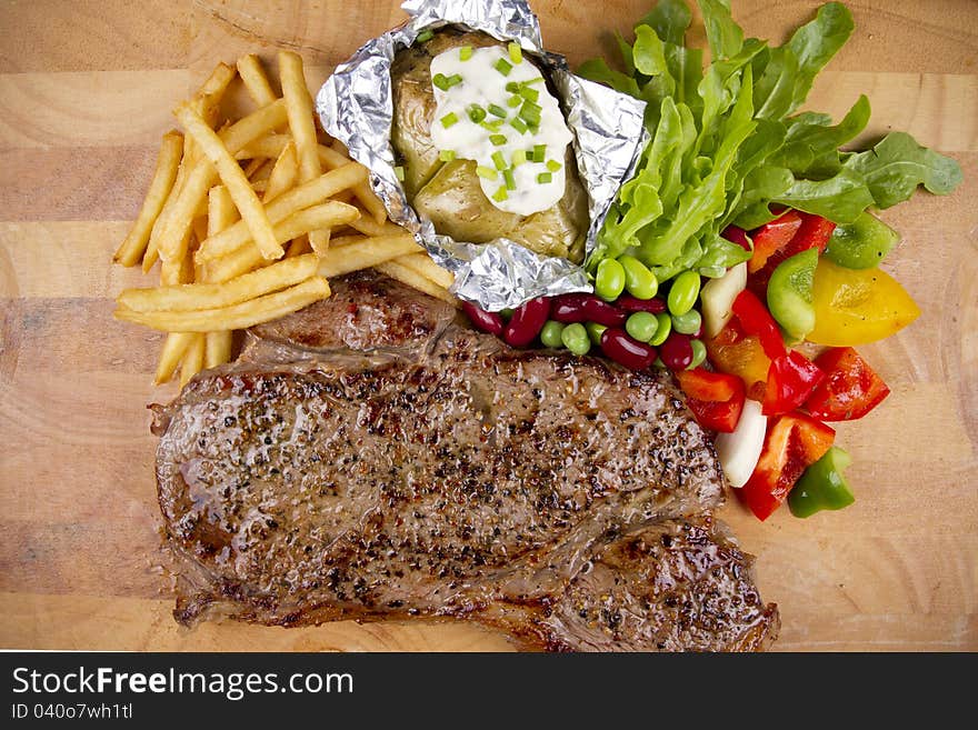 Set of steak with salad, fries and baked potato.