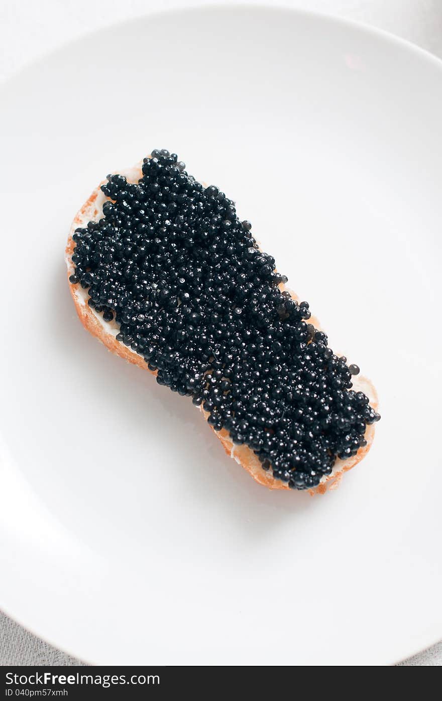 White bread with caviar on a ceramic plate