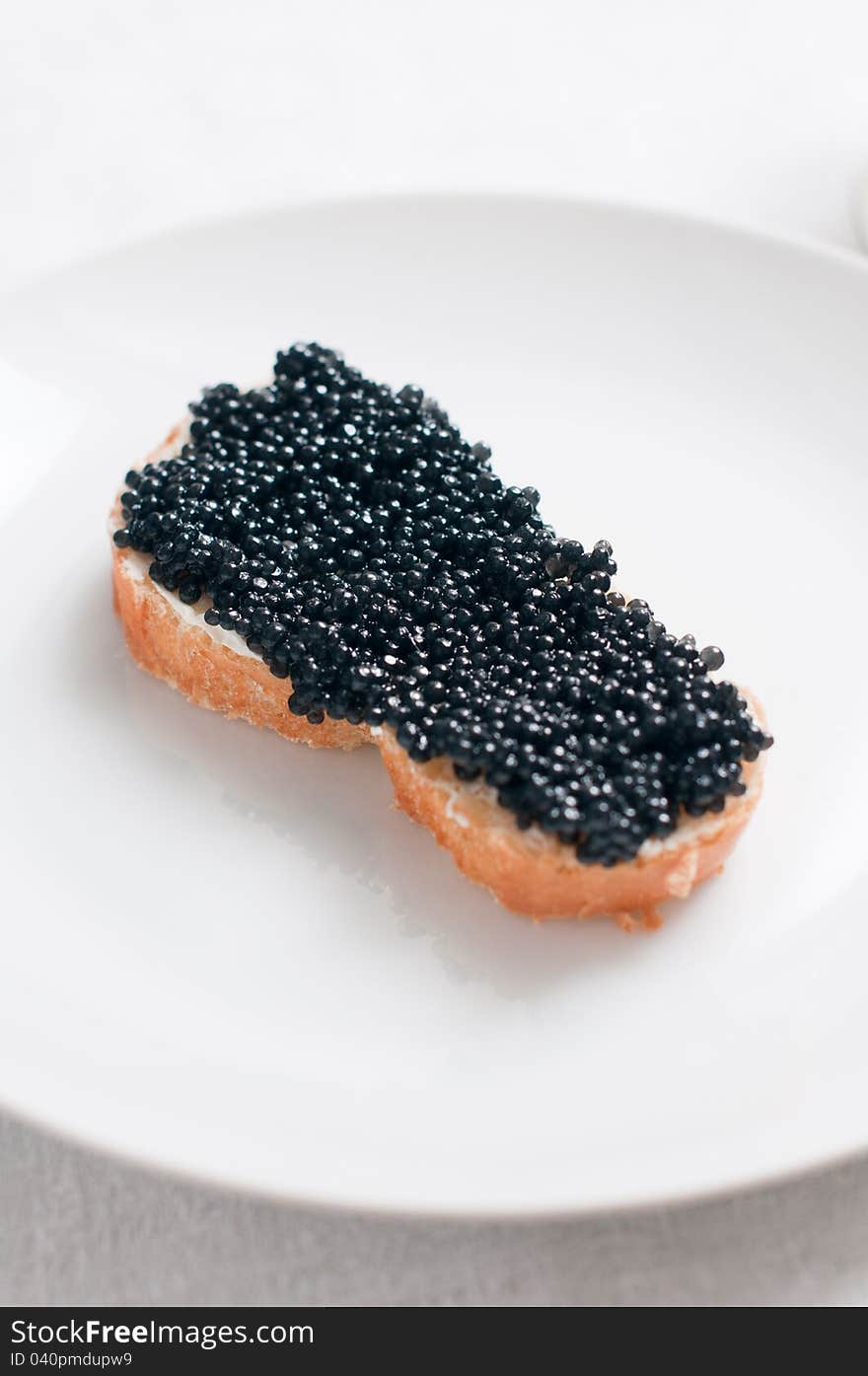 White bread with caviar on a ceramic plate