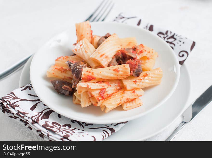 Pasta with meat on a white plate and a thick tomato sauce