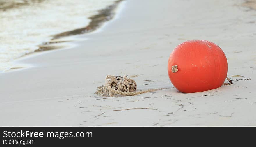 Red ball on the beach with rope waiting for the water to come up