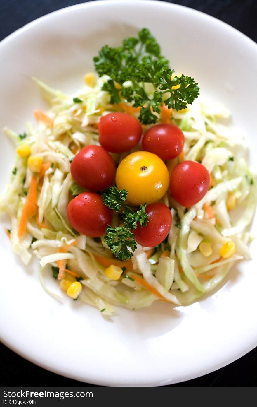 Plate of colourful fresh cabbage salad: corn, carrot, parsley, and cherry tomatoes. Plate of colourful fresh cabbage salad: corn, carrot, parsley, and cherry tomatoes