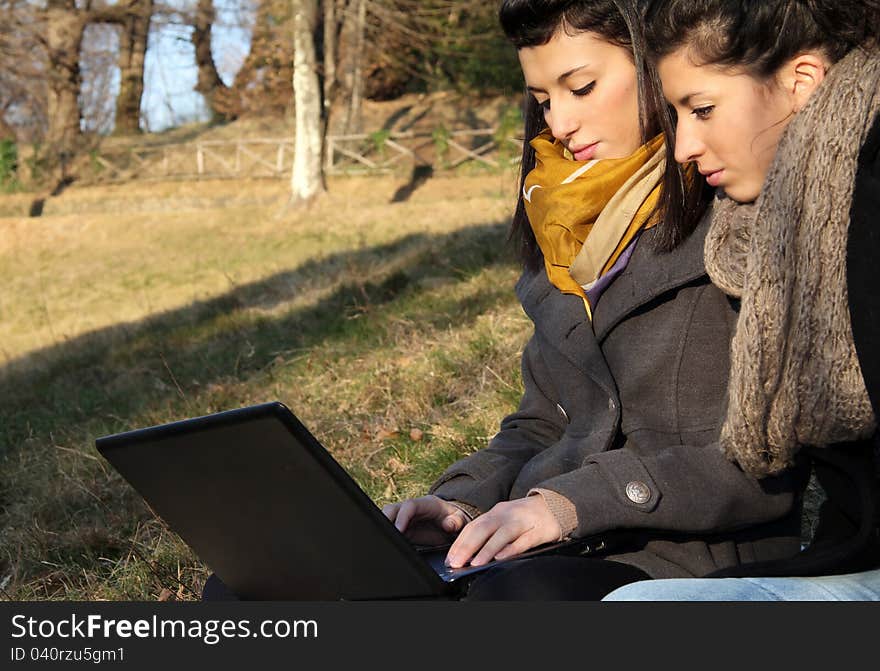 Two young girl surfing the web outdoor on the grass. Two young girl surfing the web outdoor on the grass