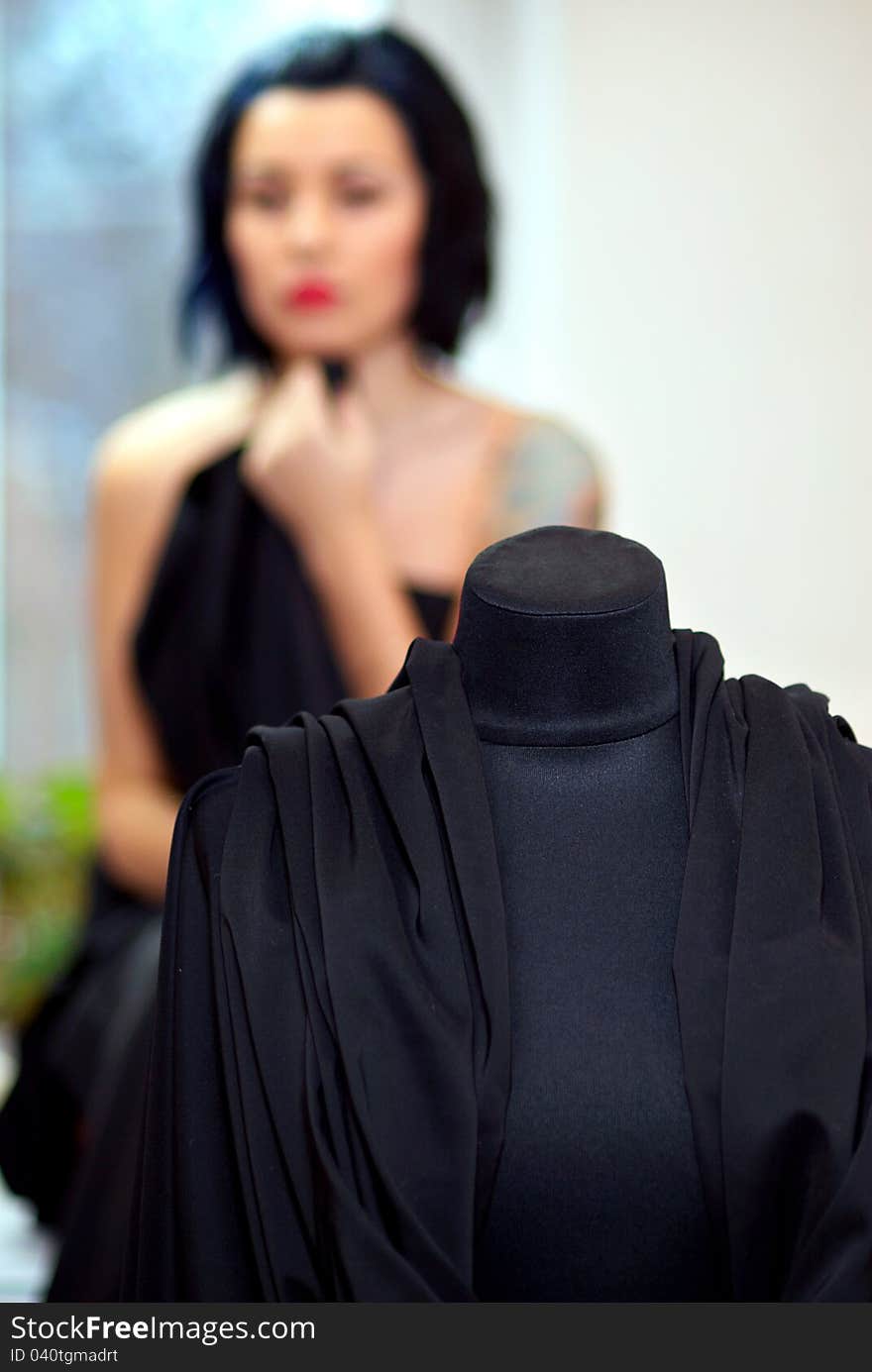 Mannequin wrapped with black cloth with girl on the background out of focus in seamstress's workshop