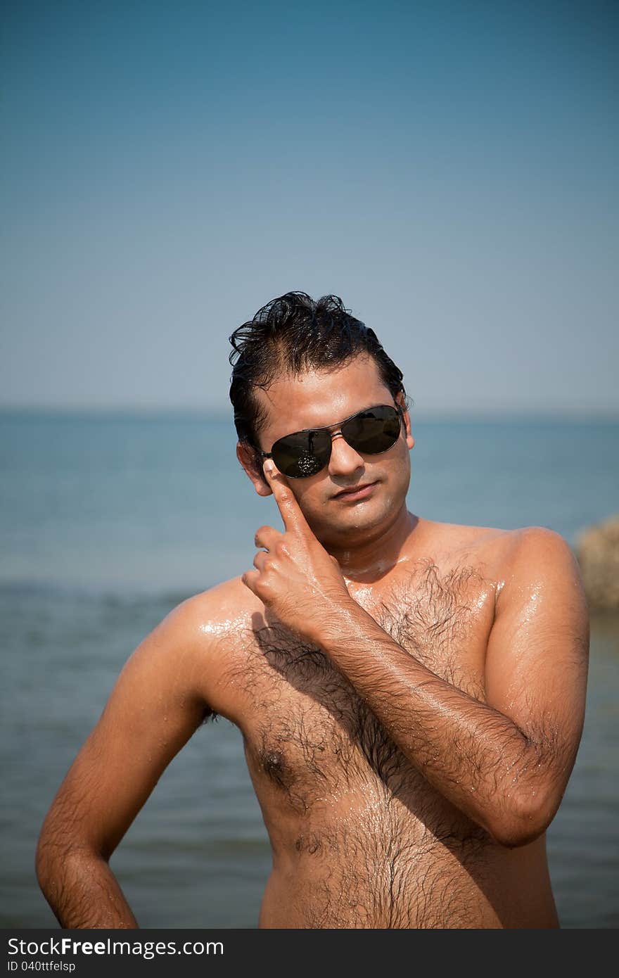 Indian Happy young man getting out of the water with sunglasses. Indian Happy young man getting out of the water with sunglasses