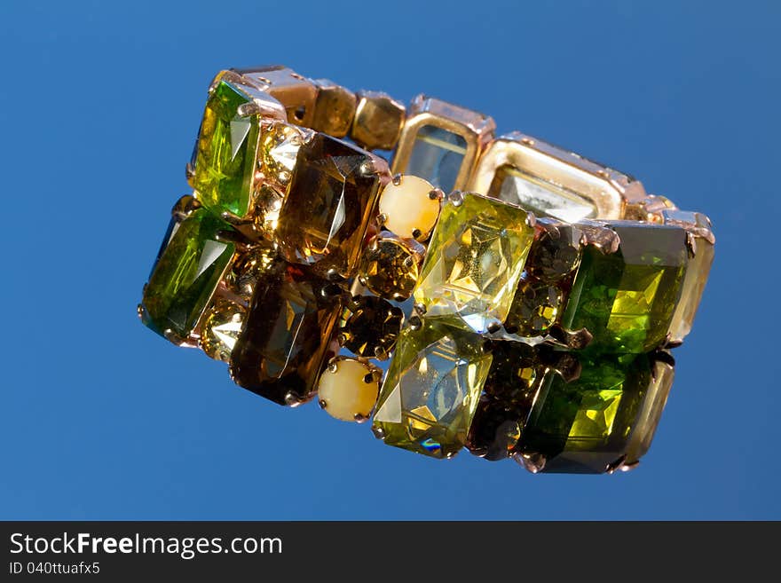 Bracelet with gemstone set on a blue background with a reflection.