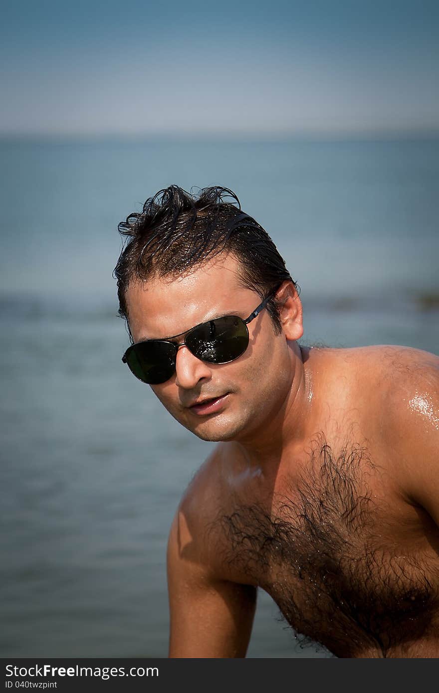 Indian Happy young man getting out of the water with sunglasses. Indian Happy young man getting out of the water with sunglasses