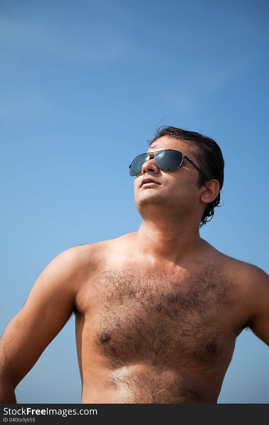 Indian Happy young man getting out of the water with sunglasses under blue sky. Indian Happy young man getting out of the water with sunglasses under blue sky