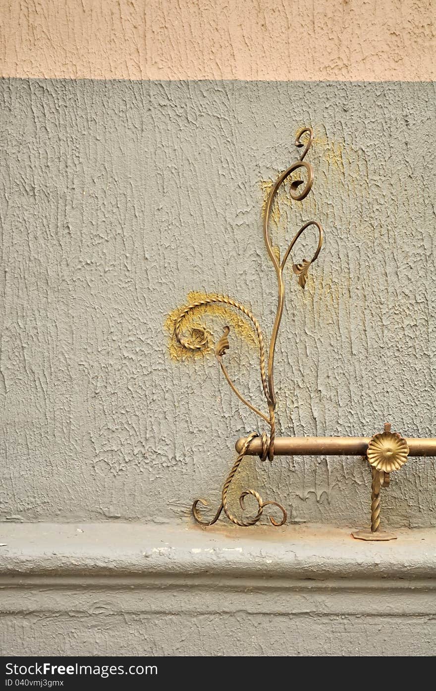 A decorative wrought iron element (handrail) on the exterior wall of a building. A decorative wrought iron element (handrail) on the exterior wall of a building