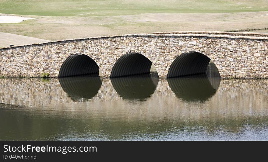 Small stone bridge refects in a pond