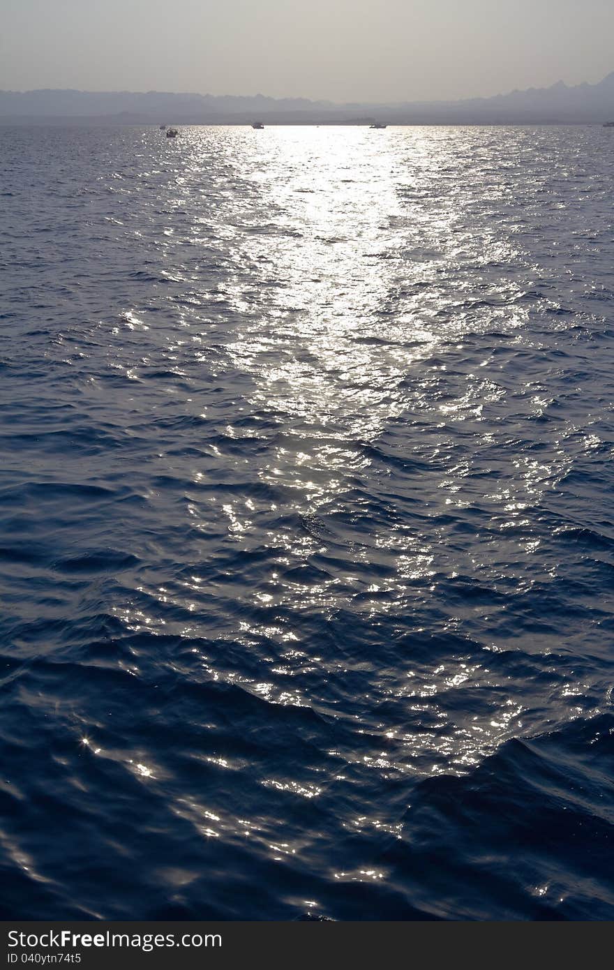 Sea water ripples with horizon and sun track