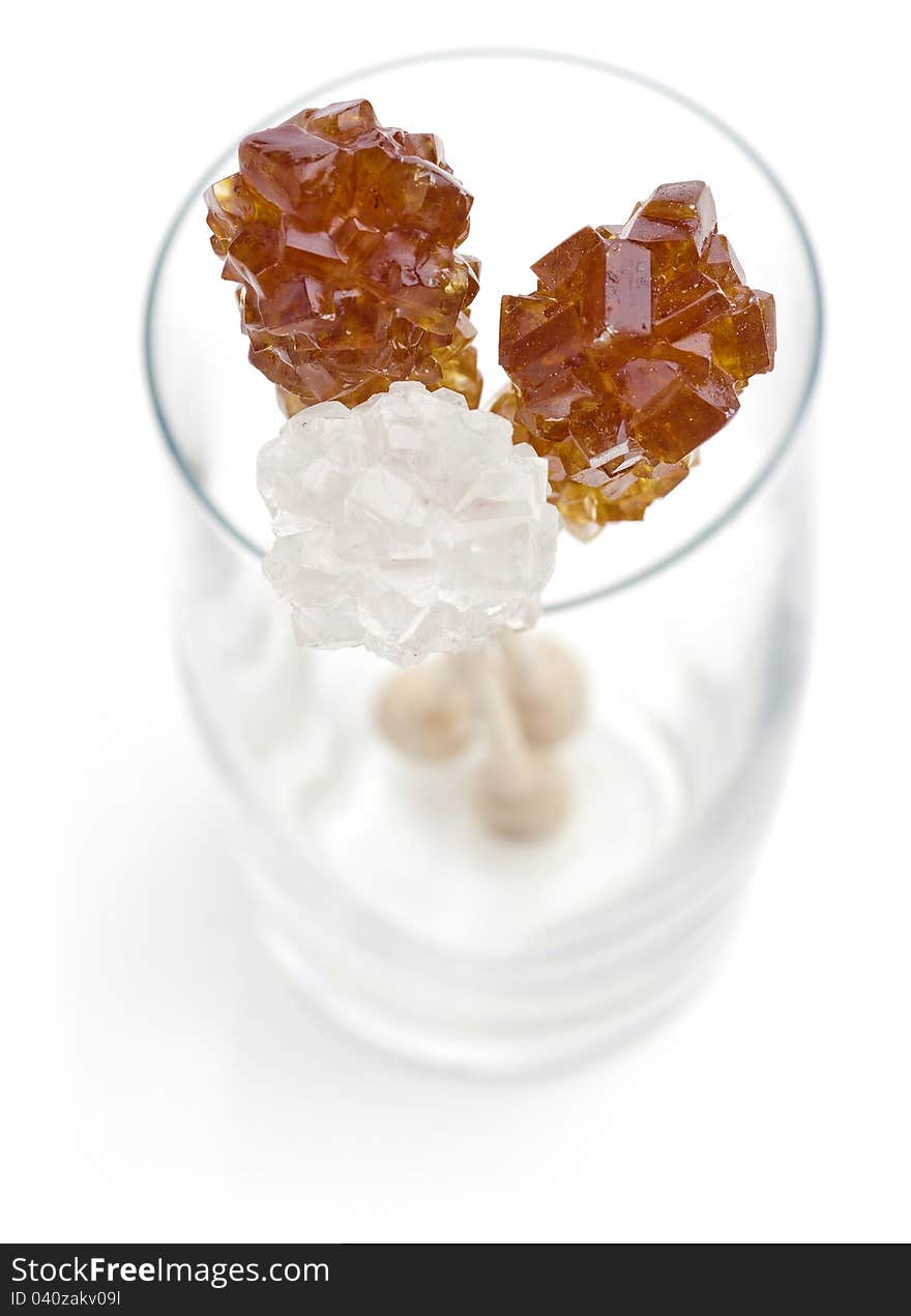 Candy brown and white sugar on a sticks in glass. Soft focus. With white background.