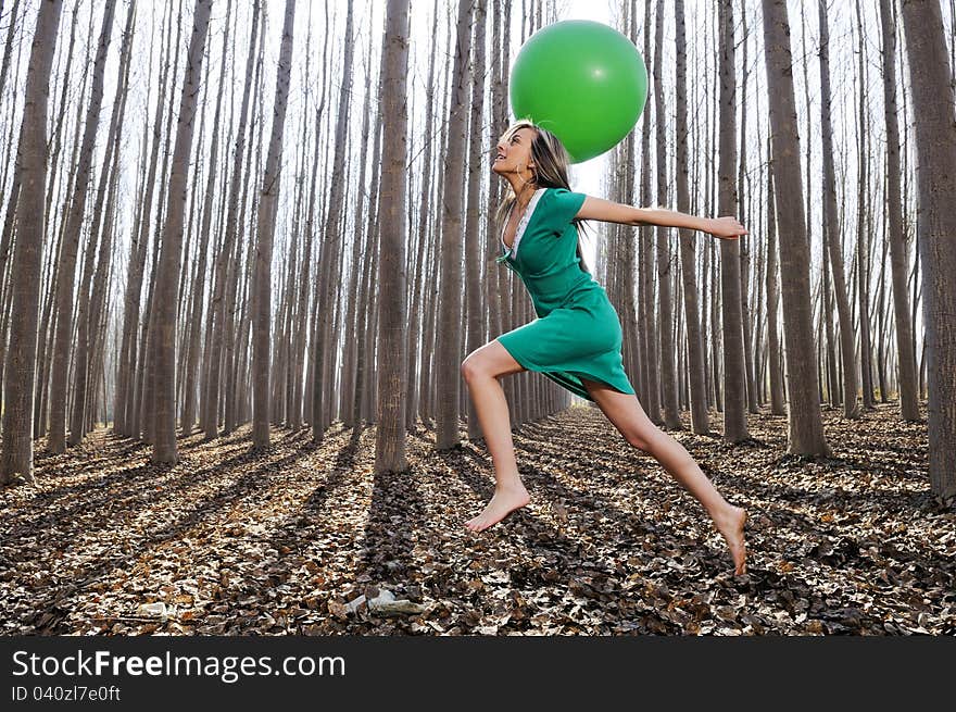 Beautiful blonde girl, dressed in green, jumping into the woods with a balloon in Fuente Vaqueros, Granada, Spain. Beautiful blonde girl, dressed in green, jumping into the woods with a balloon in Fuente Vaqueros, Granada, Spain