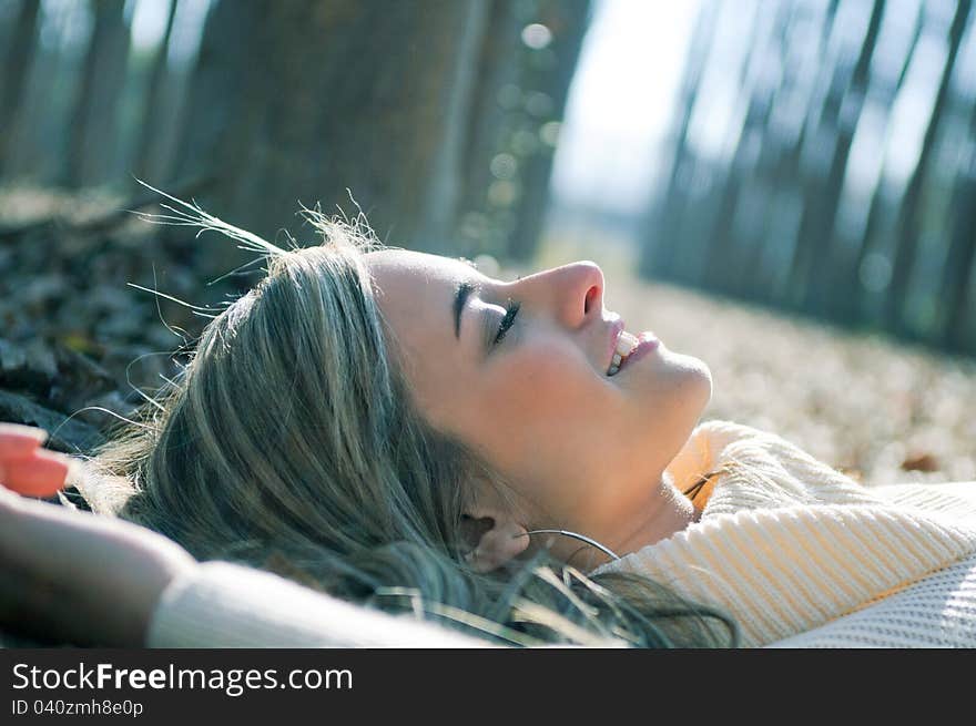 Smiling blonde girl lying on leaves in a forest of poplars. Smiling blonde girl lying on leaves in a forest of poplars