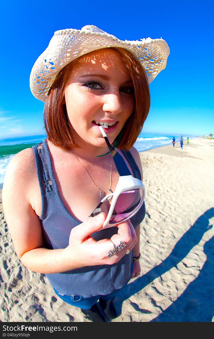 Red Head Girl biting glasses on the beach in HDR