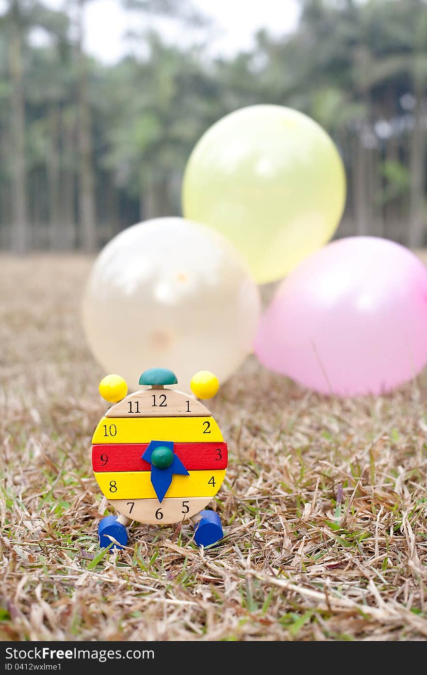 Wood clock on grass with colorful balloons. Wood clock on grass with colorful balloons