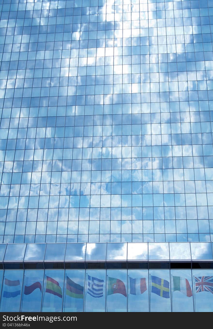 Storm clouds over the European Union concept - glass building facade reflecting flags and sky