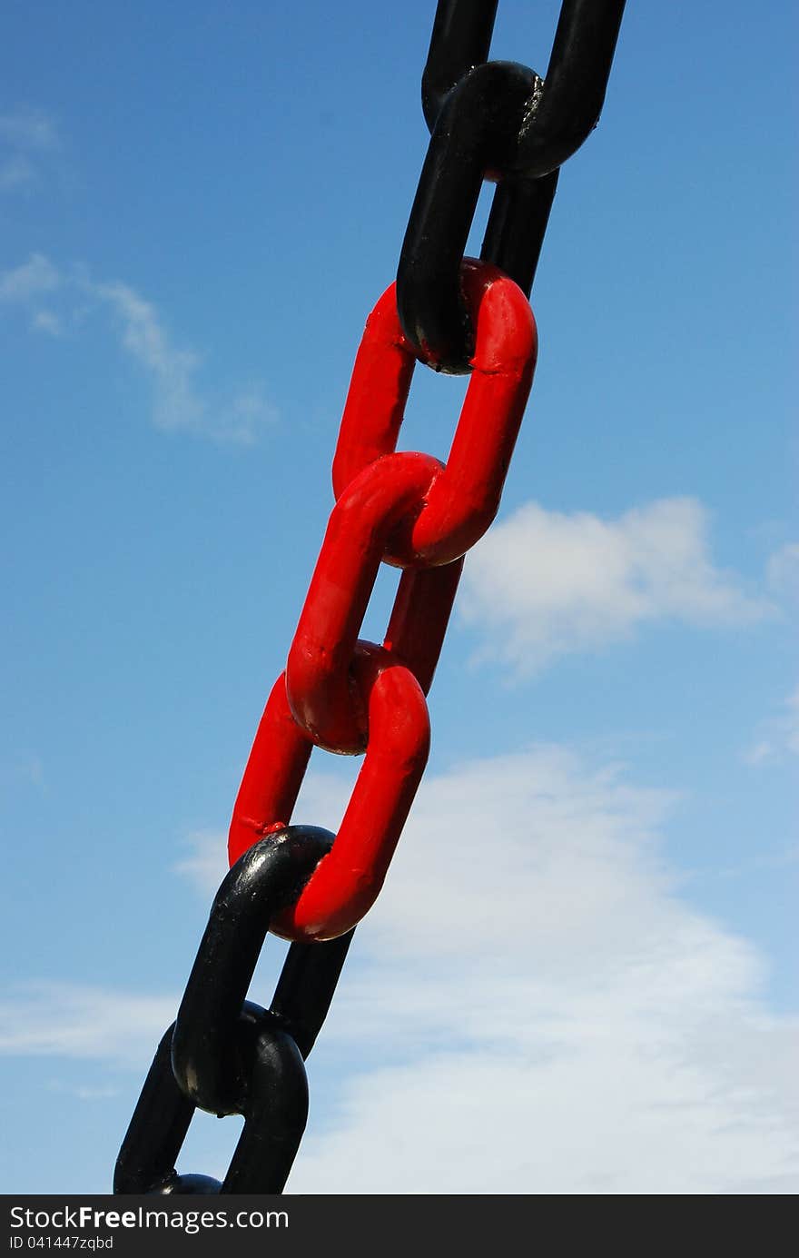 Red and black colored chain with blue sky on background