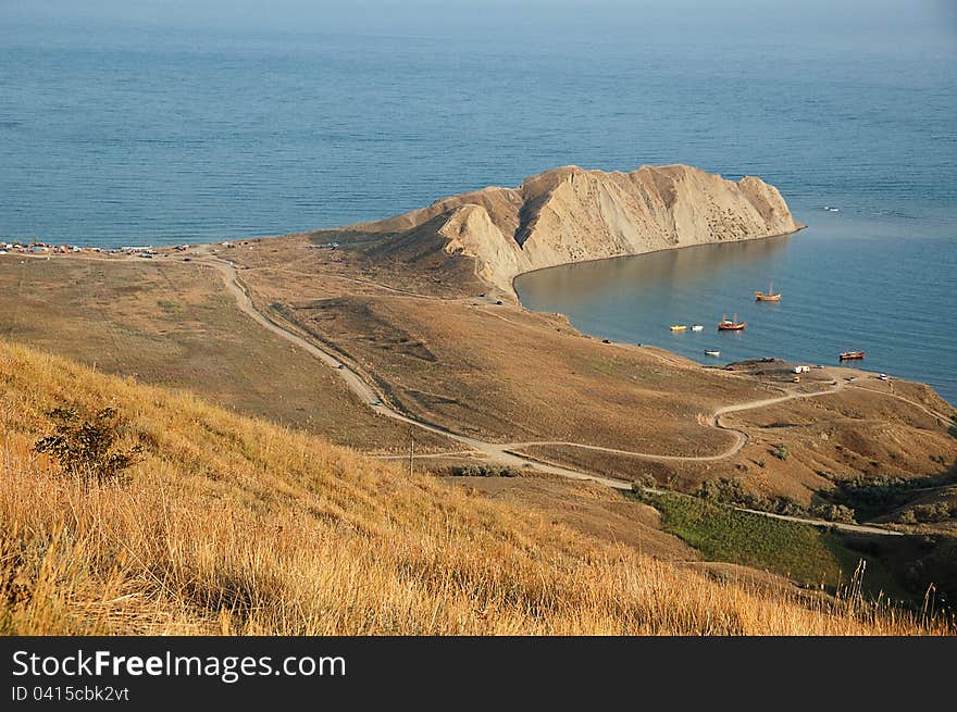 View from hill at coastline with mountains in distance. View from hill at coastline with mountains in distance