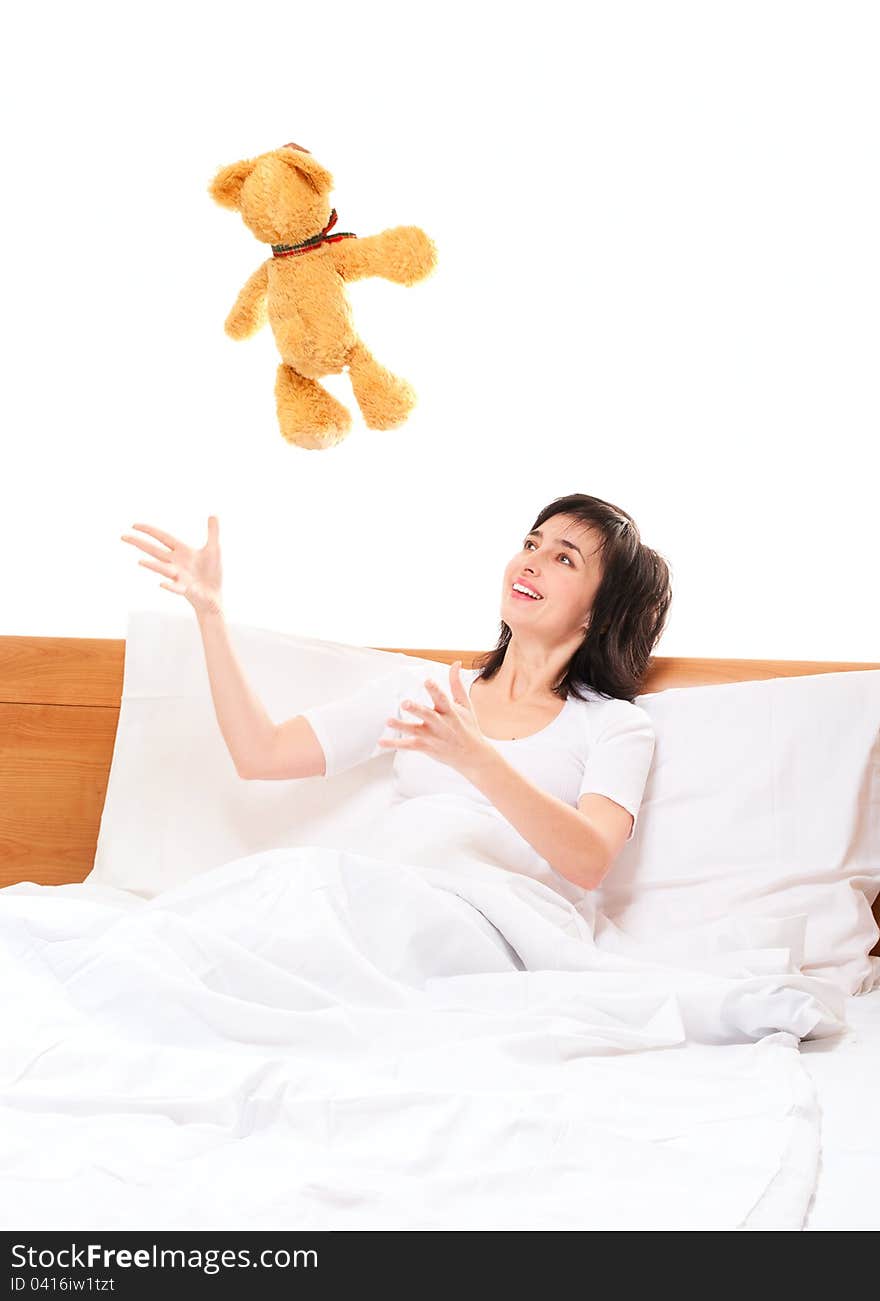 Woman in bed throwing teddy bear