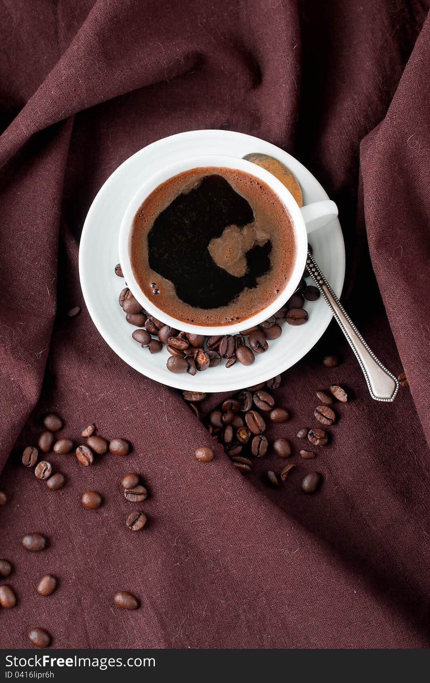 Hot coffee and coffee beans on a brown linen