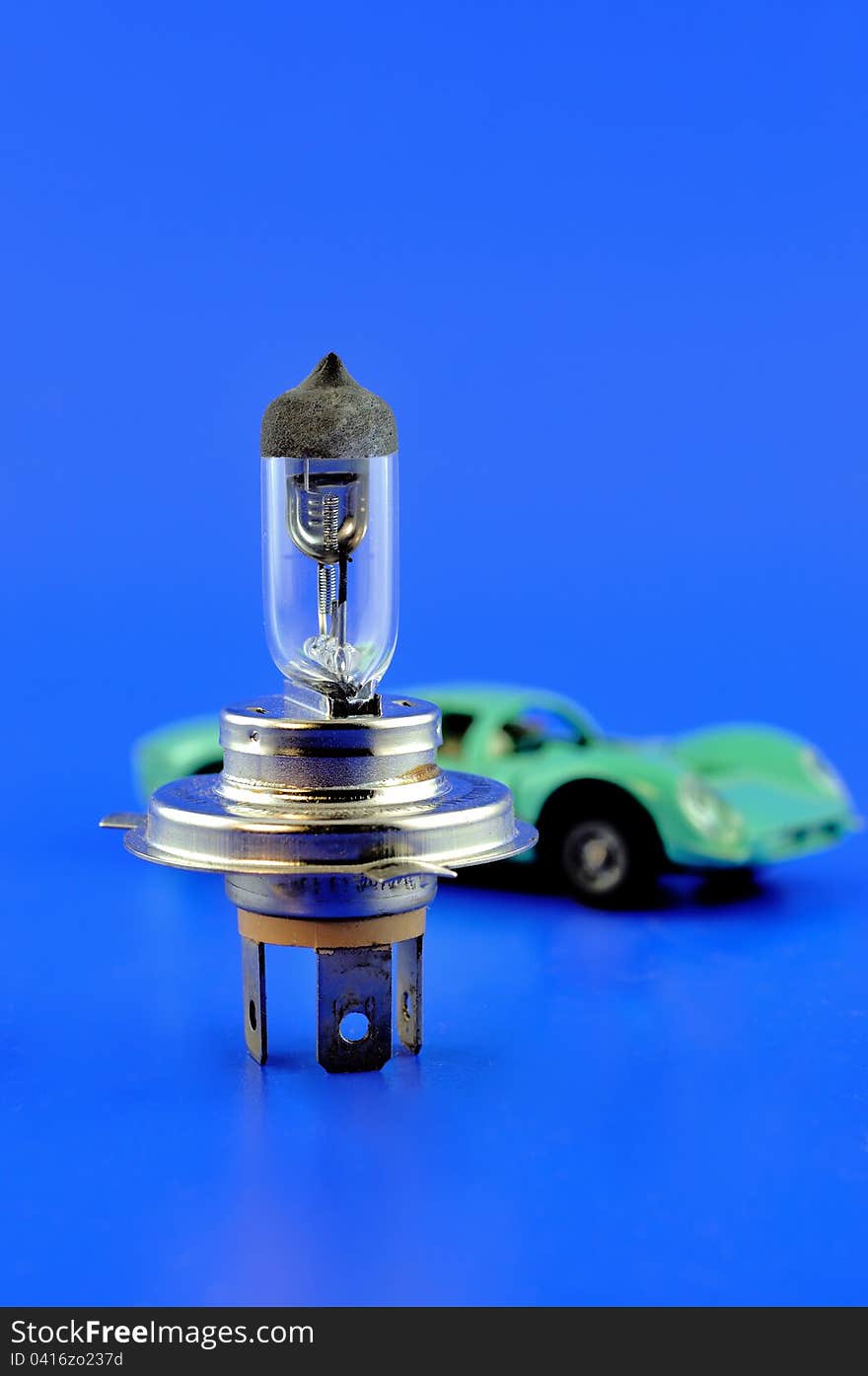 Car halogen bulb stands in the foreground and on the back of the car model. Car halogen bulb stands in the foreground and on the back of the car model