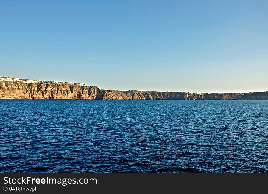 A high stone wall overlooking the sea. This stone stands in front of the island of Santorini travelers. Its shores are steep and precipitous. A high stone wall overlooking the sea. This stone stands in front of the island of Santorini travelers. Its shores are steep and precipitous.