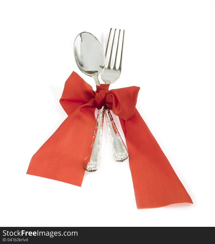 Spoon and fork are bandaged by a red ribbon. Spoon and fork are bandaged by a red ribbon