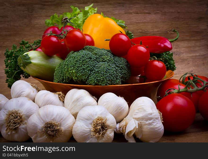 Fresh vegetables in the bowl on the wooden background