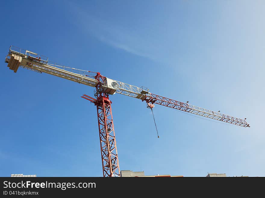 Construction crane at the construction site, on a cloudless sky