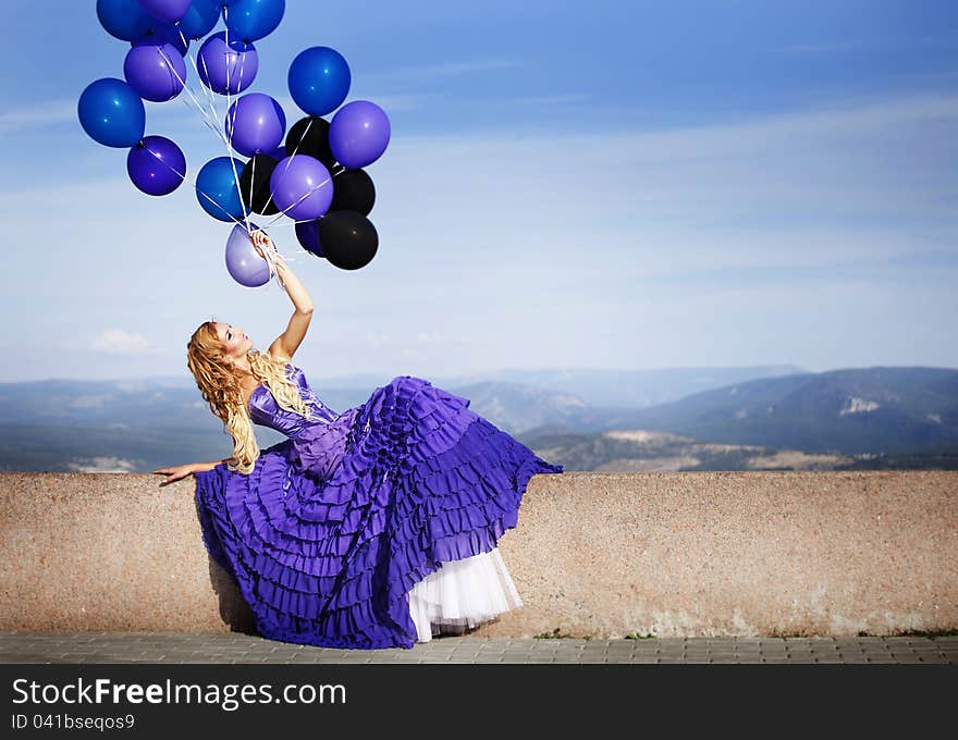 Beautiful girl in the purple dress with balloons