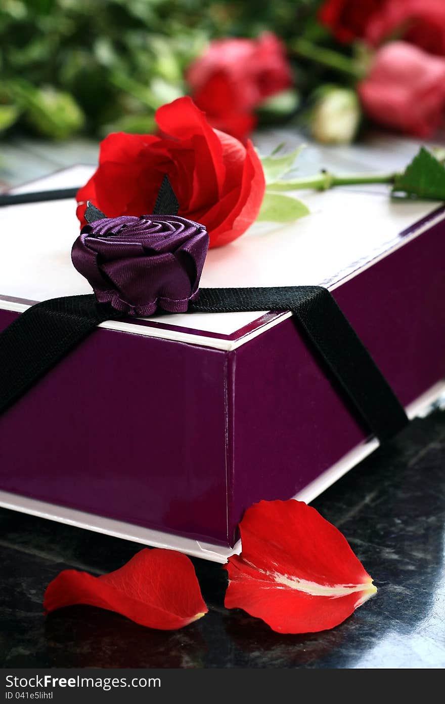 Image of a rose with a box of chocolates sitting on a table in daylight. Image of a rose with a box of chocolates sitting on a table in daylight