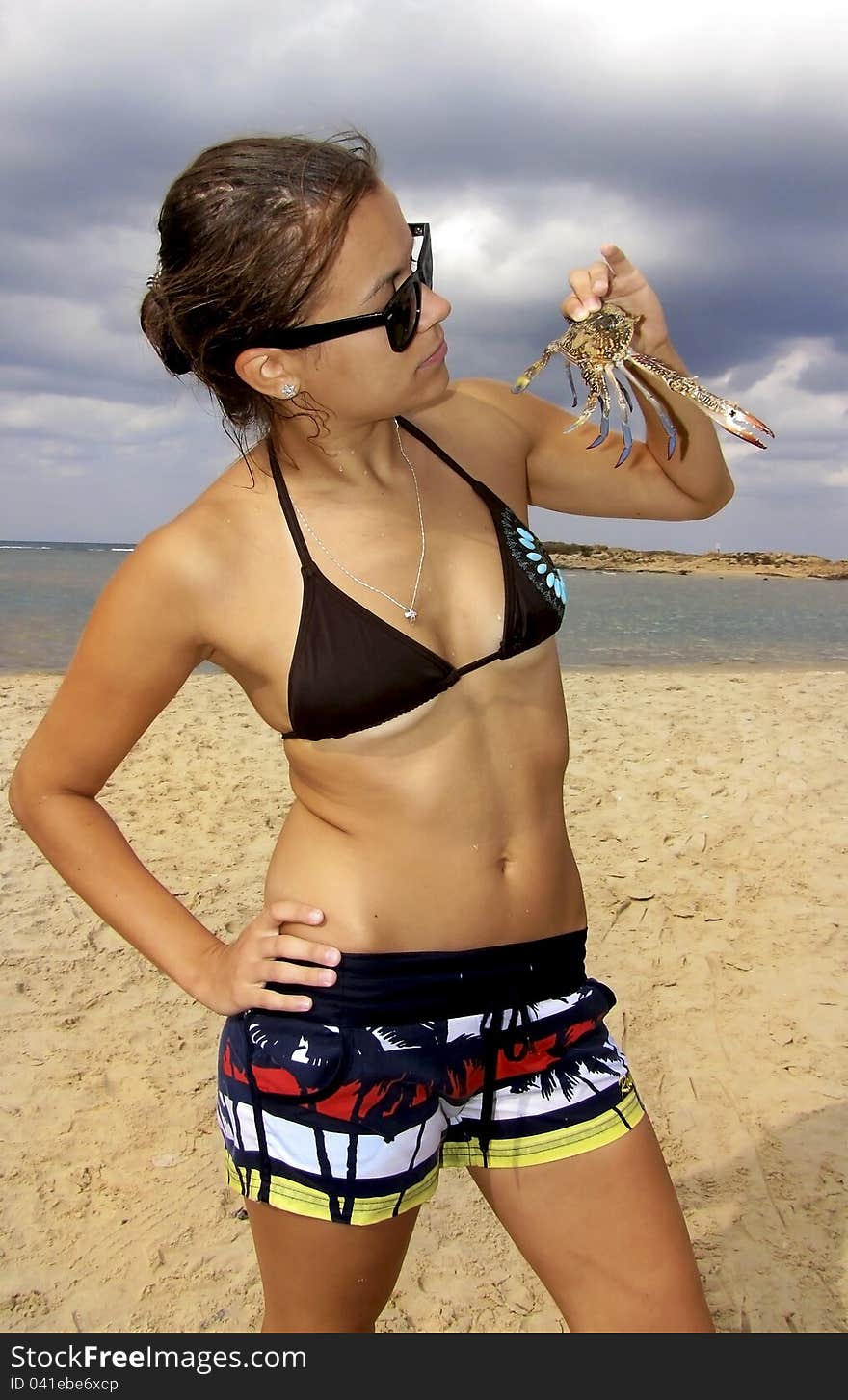 Young girl standing on the beach and holding a blue crab. Young girl standing on the beach and holding a blue crab