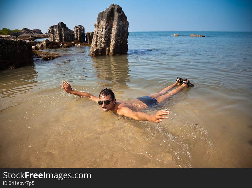 Indian man swimming at ocean beach with sunglasses