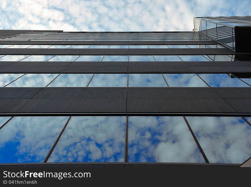 Portrait of modern office building with windows reflecting a cloudy sky. Portrait of modern office building with windows reflecting a cloudy sky